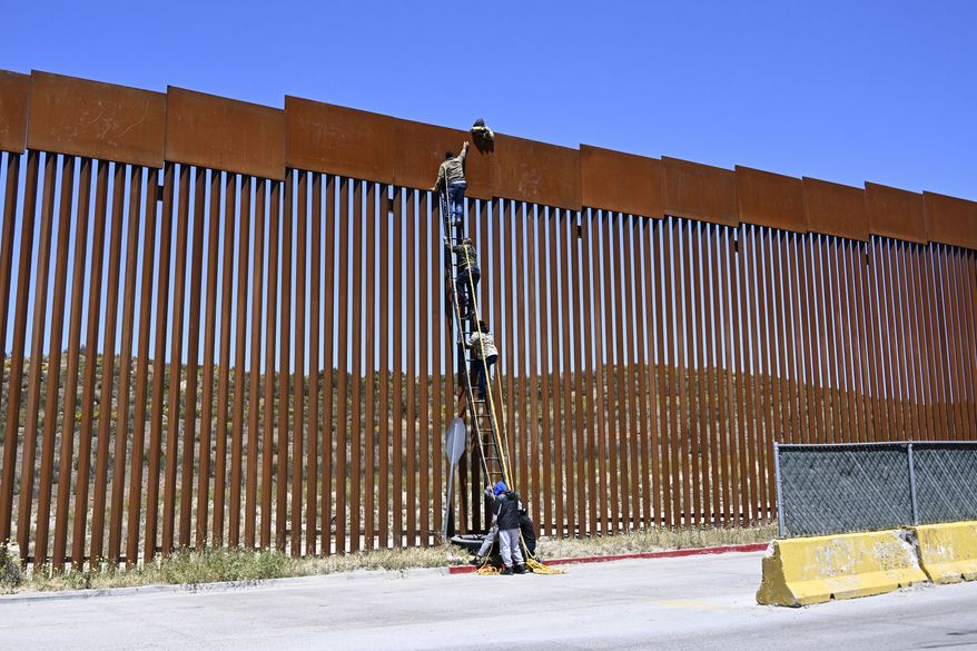 People use a ladder to scale the border fence at the US/Mexico border in Tecate, Mexico, Thursday, April 21, 2022. The men used the ropes to lower themselves down on the United States side. (AP Photo/Denis Poroy) **FILE**