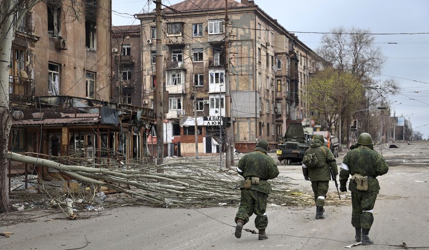 Servicemen of the militia from the Donetsk People&#x27;s Republic walk past damaged apartment buildings near the Illich Iron &amp; Steel Works Metallurgical Plant, the second-largest metallurgical enterprise in Ukraine, in an area controlled by Russian-backed separatist forces in Mariupol, Ukraine, Saturday, April 16, 2022. Mariupol, which is part of the industrial region in eastern Ukraine known as the Donbas, has been a key objective for Russia since the start of the Feb. 24 invasion. (AP Photo/Alexei Alexandrov)
