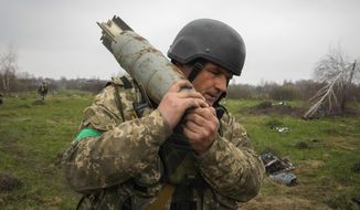 A Ukrainian soldier carries an unexploded Russian air bomb in the village of Kolonshchyna, Ukraine, Thursday, April 21, 2022. (AP Photo/Efrem Lukatsky)