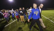 Bremerton High assistant football coach Joe Kennedy, front, walks off the field with his lawyer, right, Oct. 16, 2015, after praying at the 50-yard line following a football game in Bremerton, Wash. After losing his coaching job for refusing to stop kneeling in prayer with players and spectators on the field immediately after football games, Kennedy will take his arguments before the U.S. Supreme Court on Monday, April 25, 2022, saying the Bremerton School District violated his First Amendment rights by refusing to let him continue praying at midfield after games. (Lindsey Wasson/The Seattle Times via AP) **FILE**