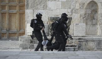 Israeli police carry a Palestinian protester during clashes at the Al Aqsa Mosque compound in Jerusalem&#39;s Old City, Friday, April 22, 2022. (AP Photo/Mahmoud Illean)