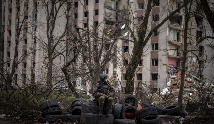 A Ukrainian soldier sits on tyres next to a building destroyed by Russian bombing in Chernihiv on Saturday, April 23, 2022. (AP Photo/Emilio Morenatti)