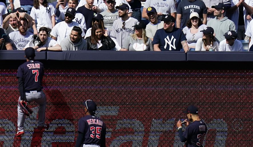 Cleveland Guardians&#x27; Myles Straw (7) climbs the left field wall to talk with a fan during the ninth inning of a baseball game against the New York Yankees Saturday, April 23, 2022, in New York. The Yankees won 5-4. (AP Photo/Frank Franklin II)