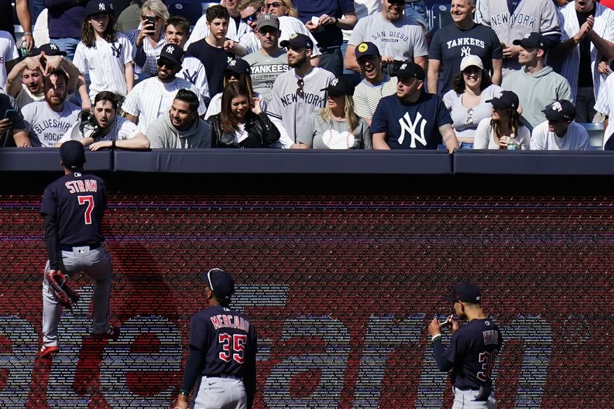 Cleveland Guardians&#x27; Myles Straw (7) climbs the left field wall to talk with a fan during the ninth inning of a baseball game against the New York Yankees Saturday, April 23, 2022, in New York. The Yankees won 5-4. (AP Photo/Frank Franklin II)