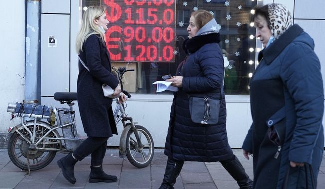 People walk past a currency exchange office screen displaying the exchange rates of U.S. Dollar and Euro to Russian Rubles in Moscow&#x27;s downtown, Russia, Feb. 28, 2022. (AP Photo/File)