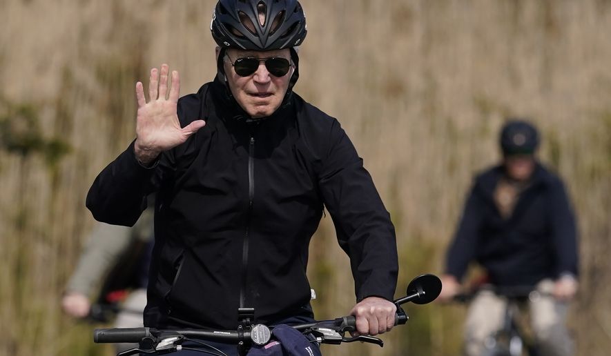 President Joe Biden waves as he rides a bicycle in Gordon&#x27;s Pond State Park in Rehoboth Beach, Del., Sunday, March 20, 2022. (AP Photo/Carolyn Kaster)