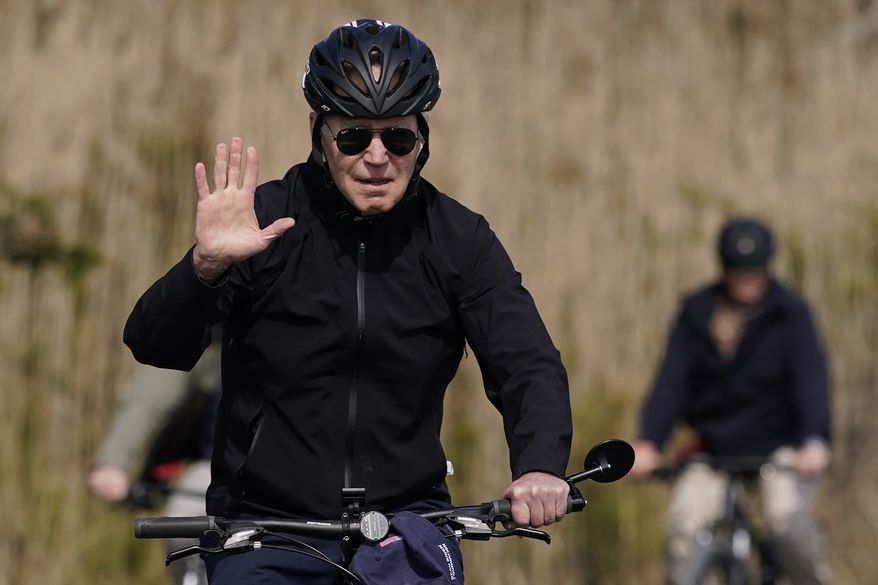President Joe Biden waves as he rides a bicycle in Gordon's Pond State Park in Rehoboth Beach, Del., Sunday, March 20, 2022. (AP Photo/Carolyn Kaster)