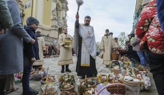 A Ukrainian priest blesses believers as they collect traditional cakes and painted eggs prepared for an Easter celebration in the in Lviv, Ukraine, Saturday, April 23, 2022. (AP Photo/Mykola Tys)