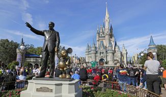 In this Jan. 9, 2019, file photo, guests watch a show near a statue of Walt Disney and Micky Mouse in front of the Cinderella Castle at the Magic Kingdom at Walt Disney World in Lake Buena Vista, part of the Orlando area in Fla. (AP Photo/John Raoux, File)