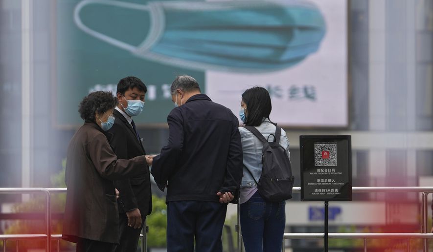 A security guard wearing a face mask stands watch as masked residents using their smartphone to scan their health code at a barricaded entrance to a commercial office complex, Sunday, April 24, 2022, in Beijing. Beijing is on alert after 10 middle school students tested positive for COVID-19, in what city officials said was an initial round of testing. (AP Photo/Andy Wong)