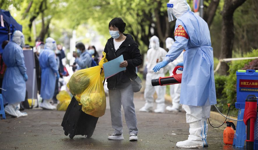 In this photo released by Xinhua News Agency, a villager carrying baggage is disinfected as she returns home after being quarantined due to local COVID-19 cases found in Lianqin Village of Beicai Town in Pudong New Area, Shanghai on Tuesday, April 26, 2022. (Jin Liwang/Xinhua via AP) ** FILE **