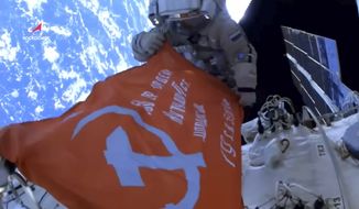 In this photo taken from video footage released by Roscosmos Space Agency, Roscosmos&#x27; cosmonauts Oleg Artemyev and Denis Matveev unfold a copy of the Soviet Victory Banner in World War II during their spacewalk on the International Space Station (ISS), Thursday, April 28, 2022. (Roscosmos Space Agency via AP)