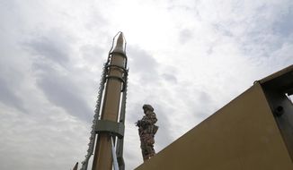 A member of the Revolutionary Guard stands in front of Shahab-3 missile which is displayed during the annual pro-Palestinian Al-Quds, or Jerusalem, Day rally in Tehran, Iran, Friday, April 29, 2022. Iran does not recognize Israel and supports Hamas and Hezbollah, militant groups that oppose it. (AP Photo/Vahid Salemi)