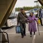 Kateryna Hodza, 85, and her grandson Artem Dorschenko arrive at a reception center for displaced people in Zaporizhzhia, Ukraine, Friday, April 29, 2022. The world is now accustomed to images of millions of Ukrainians on the run from Russia’s invasion. In their shadow are people with a different kind of desperation and daring, heading the other way. (AP Photo/Francisco Seco)