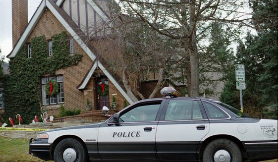 In this Jan. 3, 1997, file photo, a police officer sits in her cruiser outside the home in which 6-year-old JonBenet Ramsey was found murdered in Boulder, Colorado on Dec. 26, 1996. The father of JonBenet Ramsey, John Ramsey, is supporting an online petition asking Colorado Gov. Jared Polis to transfer DNA testing in the case away from the Boulder Police Department to an outside agency. (AP Photo/David Zalubowski, File)