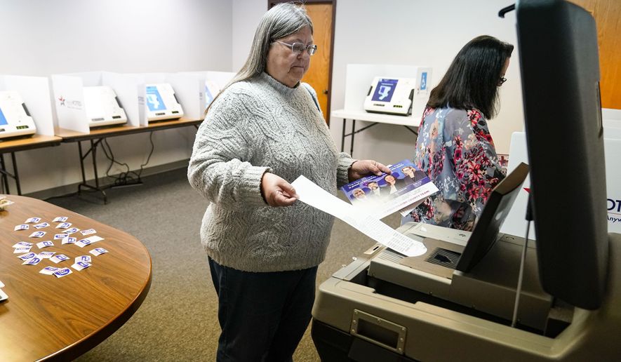 A voter inserts her ballot into a scanner as she votes in the primary election in Indianapolis, Tuesday, May 3, 2022. (AP Photo/Michael Conroy)
