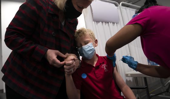 Heather Haworth, left, holds the hand of her 12-year-old son Jeremy as he receives the first dose of the Pfizer COVID-19 vaccine from medical assistant Gloria Urgell at the Providence, Edwards Lifesciences vaccination site in Santa Ana, Calif., Thursday, May 13, 2021. The California state Senate Judiciary committee approved a bill by state Sen. Scott Wiener, D-San Francisco, Thursday, May 5, 2022, that would allow minors between the ages of 12-17 to get vaccinated without parental approval. The measure now goes to the full Senate. (AP Photo/Jae C. Hong) **FILE**