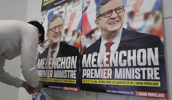 A supporter of far-left leader Jean-Luc Melenchon sticks electoral posters reading &amp;quot;Melenchon Prime Minister&amp;quot; before a local meeting, Thursday, May 5, 2022 in Lille, northern France. Jean-Luc Melenchon, who earned a third place finish in the presidential election, is trying to engineer a stunning comeback as the head of a coalition of leftist parties who have spent the past five years in the president&#39;s large shadow. Legislative elections will be held over two rounds of voting, on June 12 and 19.(AP Photo/Michel Spingler)