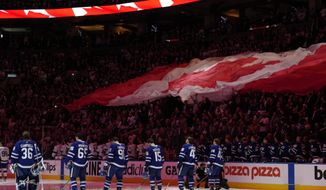 Fans and players stand for the national anthems before Game 2 of an NHL hockey Stanley Cup playoffs first-round series between the Tampa Bay Lightning and the Toronto Maple Leafs on Wednesday, May 4, 2022, in Toronto. (Frank Gunn/The Canadian Press via AP)