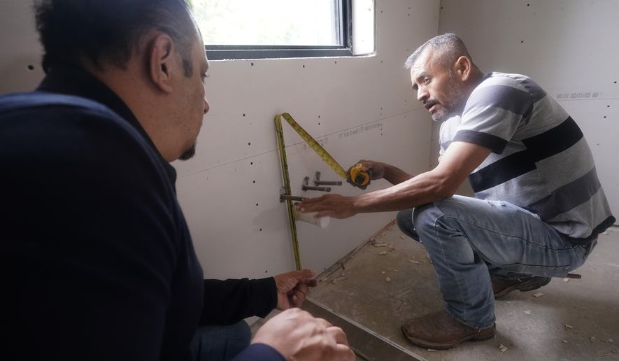 Tile subcontractor Horacio Gomez, right, originally from the Mexican state of Michoacan, measures and talks with homebuilder Joshua Correa about plans at a custom home under construction in Plano, Texas, Tuesday, May 3, 2022. (AP Photo/LM Otero) ** FILE **