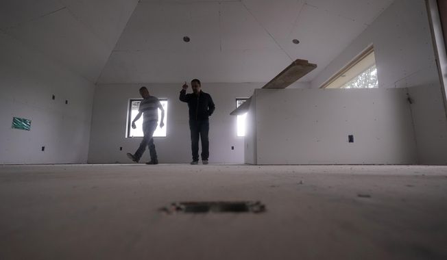 Tile subcontractor Horacio Gomez, originally from the Mexican state of Michoacan, left, confers with homebuilder Joshua Correa about plans for a floor at a custom home under construction in Plano, Texas, Tuesday, May 3, 2022. (AP Photo/LM Otero)