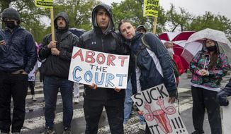 EDS NOTE: OBSCENITY - Abortion-rights protesters Greg Piteo, left, and Maeve Bradley, hold up signs during a demonstration outside of the U.S. Supreme Court, Saturday, May 7, 2022, in Washington. A draft opinion suggests the U.S. Supreme Court could be poised to overturn the landmark 1973 Roe v. Wade case that legalized abortion nationwide, according to a Politico report released Monday. Whatever the outcome, the Politico report represents an extremely rare breach of the court&#39;s secretive deliberation process, and on a case of surpassing importance. (AP Photo/Amanda Andrade-Rhoades)