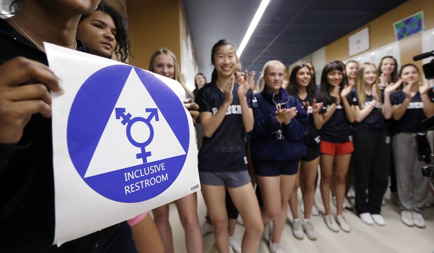 Deena Kennedy, left, holds a sticker for a new gender-neutral bathroom as members of the cheer squad applaud behind during a ceremonial opening for the restroom at Nathan Hale Jigh School Tuesday, May 17, 2016, in Seattle. (AP Photo/Elaine Thompson) **FILE**