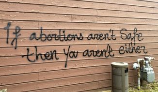 Threatening graffiti is seen on the exterior of Wisconsin Family Action offices in Madison, Wis., on Sunday, May 8, 2022. The Madison headquarters of the anti-abortion group was vandalized late Saturday or early Sunday, according to an official with the group. (Alex Shur/Wisconsin State Journal via AP)