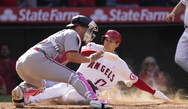 Los Angeles Angels designated hitter Shohei Ohtani (17) scores off of a walk-off single hit by Anthony Rendon during the ninth inning of a baseball game against the Washington Nationals in Anaheim, Calif., Sunday, May 8, 2022. Washington Nationals catcher Riley Adams is at left. (AP Photo/Ashley Landis)