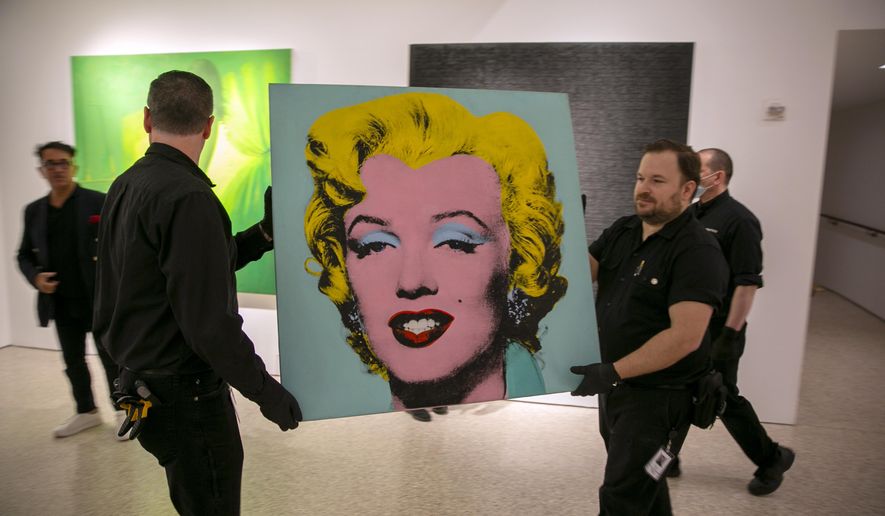 The 1964 painting Shot Sage Blue Marilyn by Andy Warhol is carried in Christie&#39;s showroom in New York City on Sunday, May 8, 2022. The auction house predicts it will sell for $200 million on Monday, becoming the most expensive 20th-century artwork to sell at auction. (AP Photo/Ted Shaffrey)