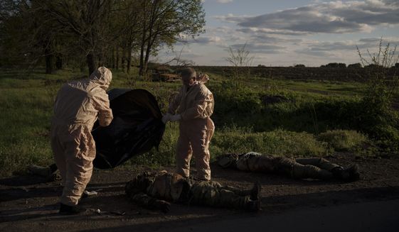 Emergency workers prepare to remove the bodies of Russian soldiers in the village of Vilkhivka, recently retaken by Ukrainian forces near Kharkiv, Ukraine, Monday, May 9, 2022. (AP Photo/Felipe Dana)