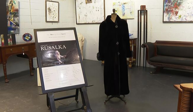 In this image from video, a black mink fur coat, right, and a signed opera poster belonging to the late Justice Ruth Bader Ginsburg, are seen inside Potomack Company Auctions in Alexandria, Va., Monday, April 11, 2022. An online auction of 150 of items owned by Ginsburg raised $803,650 for Washington National Opera. The opera was one of the late justice’s passions. (AP Photo/Nathan Ellgren, File)