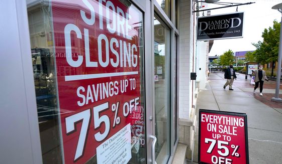 Passers-by walk past a business storefront with store closing and sale signs in Dedham, Mass.  (AP Photo/Steven Senne)