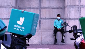 FILE - A food-delivery worker for Deliveroo takes a moment as he returns to work in Dubai, United Arab Emirates, May 2, 2022. Food-delivery workers across Dubai protesting meager pay and inadequate protections have walked off the job across the city, the company confirmed on Tuesday, May 10, 2022, marking the second strike in as many weeks in an emirate that outlaws dissent. (AP Photo/Isabel Debre, File)