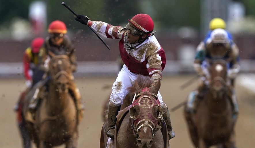 Sonny Leon celebrates after riding Rich Strike past the finish line to win the 148th running of the Kentucky Derby horse race at Churchill Downs Saturday, May 7, 2022, in Louisville, Ky. (AP Photo/Charlie Neibergall)