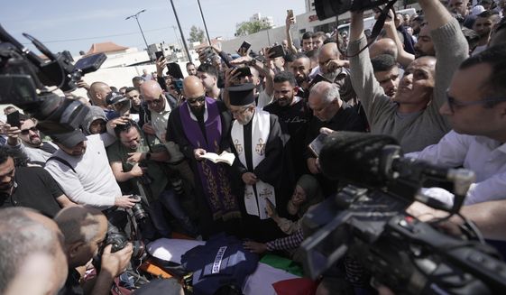 Christian priests pray over the body of Al Jazeera journalist Shireen Abu Akleh, surrounded by other journalists, in the West Bank town of Jenin, Wednesday, May 11, 2022. The well-known Palestinian reporter for the broadcaster&#39;s Arabic language channel was shot and killed while covering an Israeli raid in the occupied West Bank town of Jenin early Wednesday. (AP Photo/Majdi Mohammed)