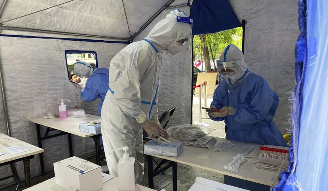 Workers in protective overalls conduct mass COVID testing for residents on Wednesday, May 11, 2022, in Beijing. (AP Photo/Ng Han Guan)