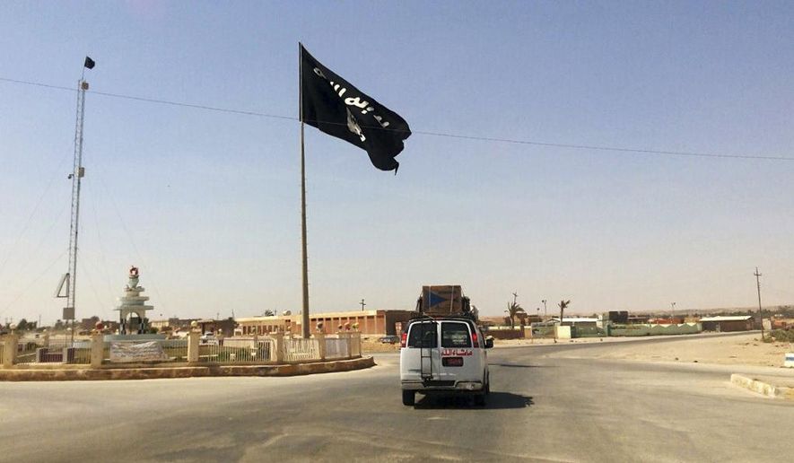 A motorist passes by a flag of the Islamic State group in central Rawah, 175 miles (281 kilometers) northwest of Baghdad, Iraq, July 22, 2014. (AP Photo) **FILE**