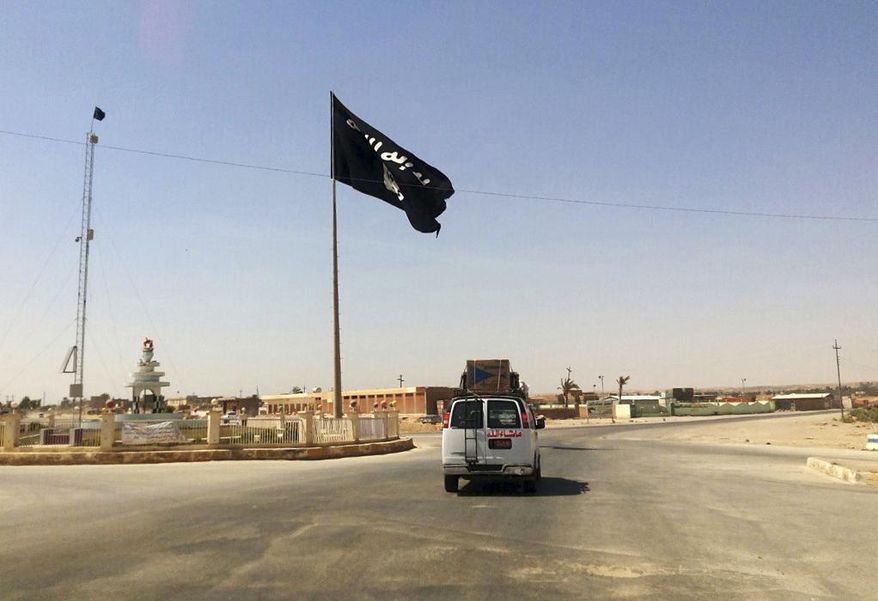 A motorist passes by a flag of the Islamic State group in central Rawah, 175 miles (281 kilometers) northwest of Baghdad, Iraq, July 22, 2014. (AP Photo) **FILE**