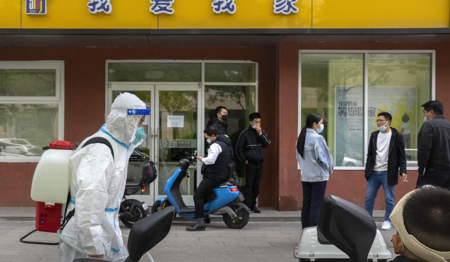 A worker wearing a protective suit and carrying a tank of disinfectant walks along a street in Beijing, Wednesday, May 11, 2022. Shanghai reaffirmed China&#x27;s strict &amp;quot;zero-COVID&amp;quot; approach to pandemic control Wednesday, a day after the head of the World Health Organization said that was not sustainable and urged China to change strategies. (AP Photo/Mark Schiefelbein)