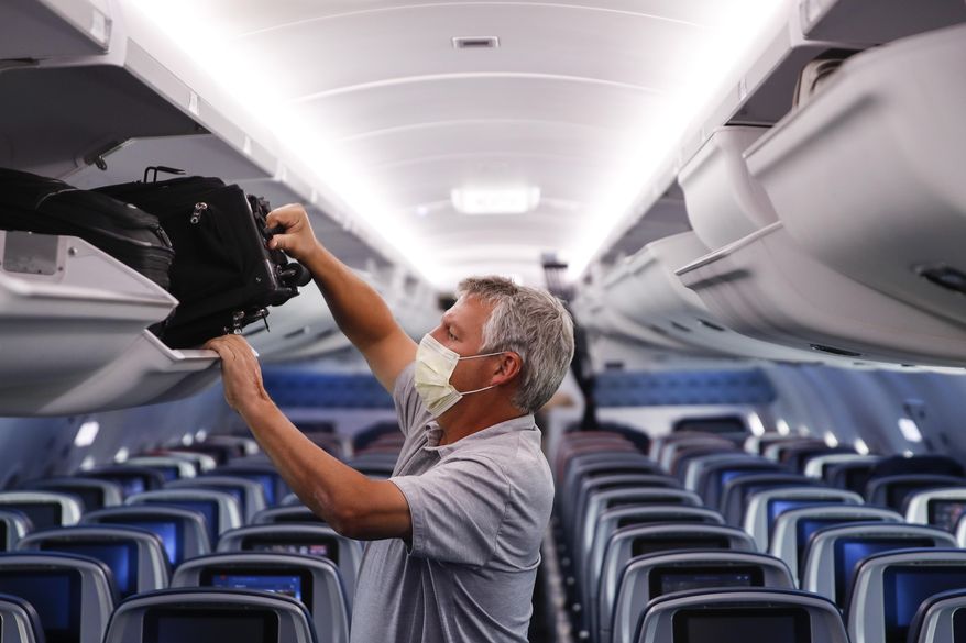 In this May 28, 2020, file photo, a passenger wears personal protective equipment on a Delta Airlines flight after landing in Minneapolis, United States of America. The European Union Aviation Safety Agency said Wednesday that from next week onward it is no longer recommending the use of medical masks at airports and on planes due to the coronavirus. (AP Photo/John Minchillo, File)