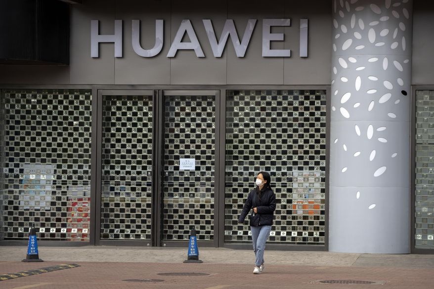 A woman wearing a face mask walks past a Huawei store temporarily closed due to coronavirus-related restrictions in Beijing, Thursday, May 12, 2022, in this file photo. (AP Photo/Mark Schiefelbein)  **FILE**