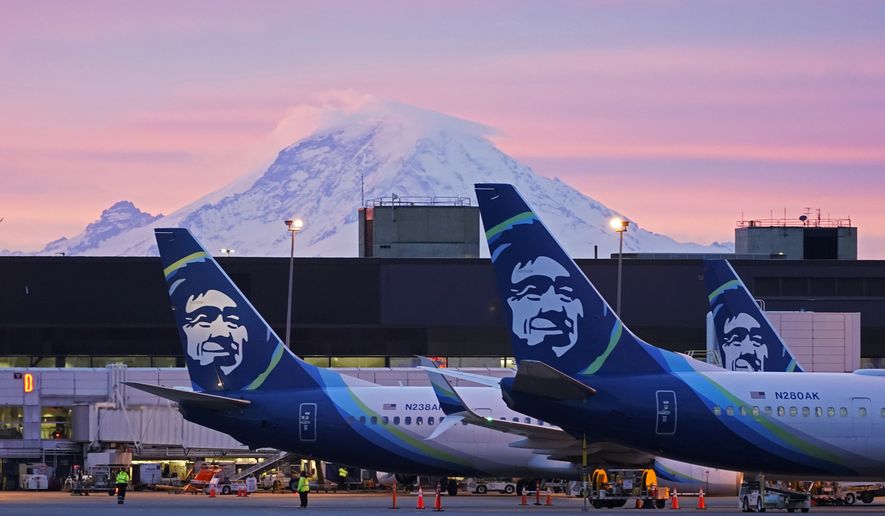 Alaska Airlines planes are parked at gates with Mount Rainier in the background at sunrise, on March 1, 2021, at Seattle-Tacoma International Airport in Seattle. The CEO of Alaska Airlines says the high level of flight cancellations since April will continue through this month. Ben Minicucci said in a message to employees Thursday, May 12, 2022, that stability should return in June. (AP Photo/Ted S. Warren, File)