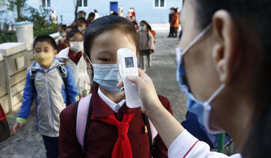 A teacher takes the body temperature of a schoolgirl to help curb the spread of the coronavirus before entering Kim Song Ju Primary School in Central District in Pyongyang, North Korea, Wednesday, Oct. 13, 2021. Before acknowledging domestic COVID-19 cases, Thursday, May 12, 2022, North Korea spent 2 1/2 years rejecting outside offers of vaccines and steadfastly claiming that its superior socialist system was protecting its 26 million people from “a malicious virus” that had killed millions around the world. (AP Photo/Cha Song Ho, File)
