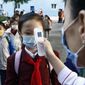 A teacher takes the body temperature of a schoolgirl to help curb the spread of the coronavirus before entering Kim Song Ju Primary School in Central District in Pyongyang, North Korea, Wednesday, Oct. 13, 2021. Before acknowledging domestic COVID-19 cases, Thursday, May 12, 2022, North Korea spent 2 1/2 years rejecting outside offers of vaccines and steadfastly claiming that its superior socialist system was protecting its 26 million people from “a malicious virus” that had killed millions around the world. (AP Photo/Cha Song Ho, File)