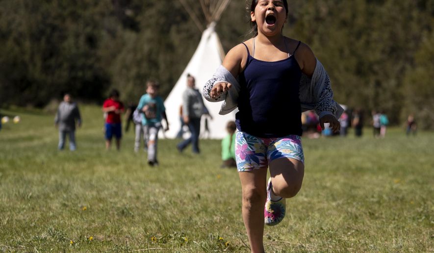 Johnnie James, a fourth grader at Pablo Elementary, participates in the run-and-scream game during the 35th annual River Honoring near Moiese, Mont., on May 11, 2022. Elementary students from schools on the Flathead Reservation participated in educational events about natural and cultural resources on the Flathead River. About 400 children a day attended the two-day event. (Ben Allan Smith/The Missoulian via AP)
