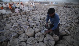 A laborer seals sacks filled with wheat in Gurdaspur, in the northern Indian state of Punjab, April 30, 2014. (AP Photo/Channi Anand, File)