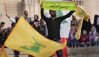 A Hezbollah supporter holds up an Arabic banner that reads: &amp;quot;At your service Nasrallah,&amp;quot; as he attends an election campaign, in Baalbek, east Lebanon, Friday, May 13, 2022. Despite a devastating economic collapse and multiple other crises gripping Lebanon, the culmination of decades of corruption and mismanagement, the deeply divisive issue of Hezbollah&#39;s weapons has been at the center of Sunday&#39;s vote for a new 128-member parliament. (AP Photo/Hussein Malla)