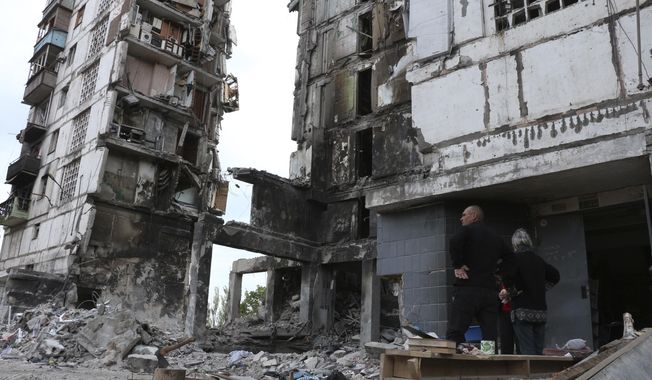 Local residents stand at the side of damaged during a heavy fighting buildings in Mariupol, in territory under the government of the Donetsk People&#x27;s Republic, eastern Ukraine, Friday, May 13, 2022. (AP Photo)