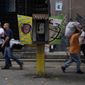 Pedestrians walk past an out of service National Telephone Company of Venezuela, CANTV, phone booth, in Caracas,Venezuela, Friday, May 13, 2022. A number of Venezuelan state-owned companies, including in the telecommunications sector, will sell up to 10% of their shares starting Monday. President Nicolas Maduro says the companies will be listed in the country&#39;s stock exchange and the sale is open to local and foreign investors. (AP Photo/Ariana Cubillos)